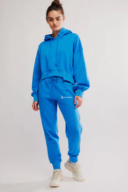 Woman wearing a blue tracksuit with a visible brand logo on a light gray background