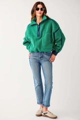 Woman wearing a green fleece pullover and blue jeans on a white background